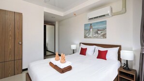 Een hotelkamer met een groot bed, een houten garderobe, een schilderij aan de muur en een airconditioner.