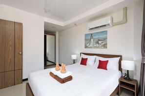 Ein Hotelzimmer mit einem großen Bett, einem Holzschrank, einem Bild an der Wand und einer Klimaanlage.