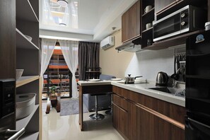 Une cuisine moderne équipée d’un four à micro-ondes encastré, d’une bouilloire et d’un réfrigérateur.