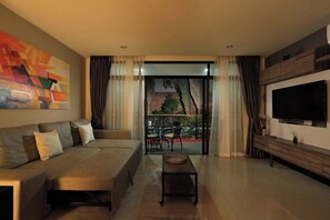 Ein modernes Wohnzimmer mit einer Couch, einem Couchtisch, einem Fernseher und einem großen Fenster mit Vorhängen.