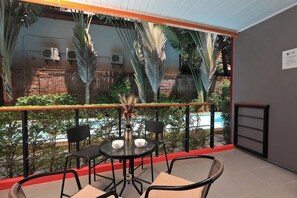 A balcony with a table and chairs, a view of a pool, and a brick wall. - Studio Pool Access Nai Harn Beach Capital Pro (Rawai)
