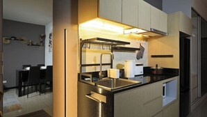 A modern kitchen with a built-in oven, a stainless steel sink, and a black countertop. - Spacious Studio Naiharn Beach Condo | CapitalPro (Rawai)