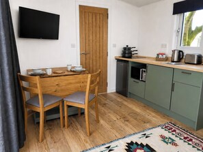 Una cocina compacta con una mesa de madera, dos sillas, lavavajillas integrado y microondas.