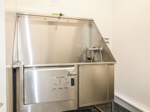 Ein Edelstahl-Spülbecken für den gewerblichen Gebrauch, ausgestattet mit einer Bedienkonsole und einem Wasserhahn.
