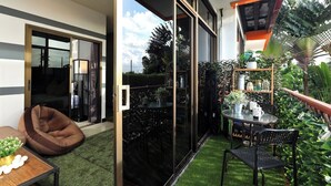 A modern room with a sliding glass door, a glass table, and a bean bag chair. - 1BR Mountain View Nai Harn Beach | Capital Pro (Rawai)