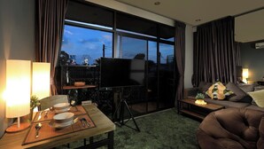 A modern hotel room with a dining area, a sofa, and a large window. - 1BR Mountain View Nai Harn Beach | Capital Pro (Rawai)