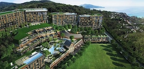 A modern hotel complex with multiple buildings, a central courtyard, and a pool area. - 1BR Mountain View Apartment Surin | CapitalPro (Surin)