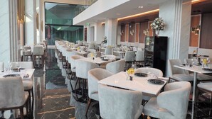 A modern restaurant with marble flooring, grey upholstered chairs, and long tables. - 1BR Mountain View Apartment Surin | CapitalPro (Surin)