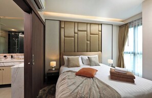Habitació d'hotel moderna amb un llit gran, un bany amb taulell de marbre i un mirall ample.