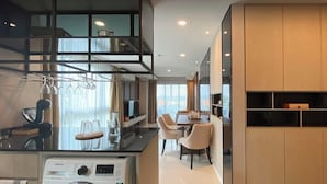 Eine moderne Küche mit Einbauwaschmaschine und -trockner, einer Essecke mit Tisch und Stühlen sowie einem großen Fenster mit Vorhängen.