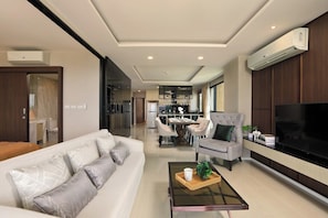 A modern living room with a sofa, armchairs, a coffee table, and a television. - 3BR Apartment Sea View Jacuzzi Surin Capital Pro (Surin)