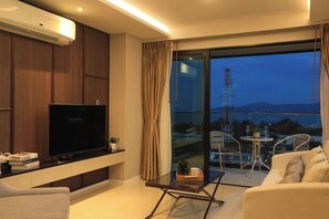 A modern living room with a flat-screen TV, a glass table, and a sofa. - 3BR Apartment Sea View Jacuzzi Surin Capital Pro (Surin)