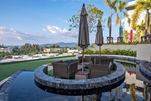 A circular water feature with seating, a view of the surrounding area, and palm trees. - 1BR Apartment Mountain View | Surin | Capital Pro (Surin)