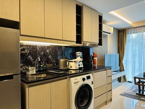 A modern kitchen with a built-in washing machine, a coffee maker, and a toaster. - 1BR Apartment Mountain View | Surin | Capital Pro (Surin)