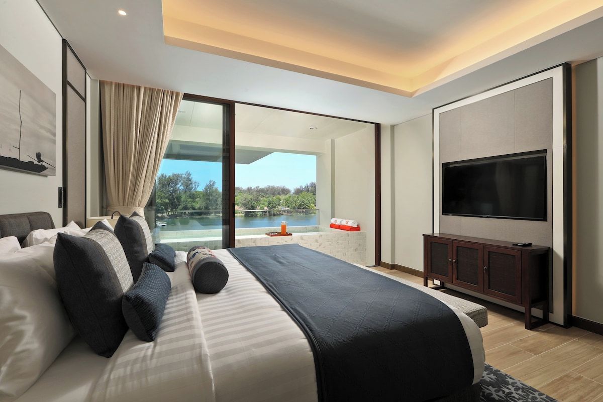 Quarto moderno com cama grande, televisão de tela plana e vista para uma piscina.
