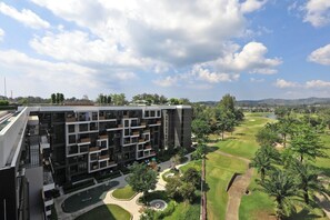 Ein modernes, mehrstöckiges Gebäude mit Innenhof, Golfplatz und einem See im Hintergrund.