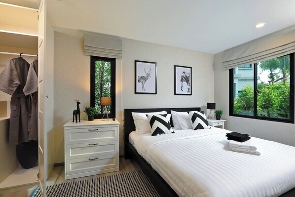 Une chambre à coucher moderne, avec un lit, des tables de chevet, une armoire et des œuvres d’art accrochées au mur.