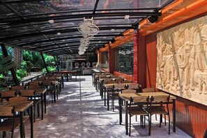 Ein Restaurant mit langen Tischen, einer Glasdecke und einer aufwendigen Wandvertiefung.
