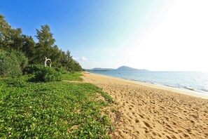 A beach with a clear sky, sandy shore, and green vegetation. - 1BR Apartment near Mai Khao Beach | CapitalPro (Mai Khao)