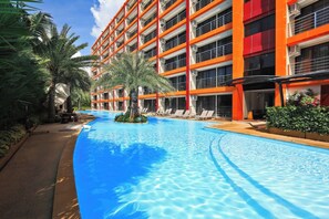 Ein Hotel mit Schwimmbad, Palmen und einem mehrstöckigen Gebäude mit Balkonen.