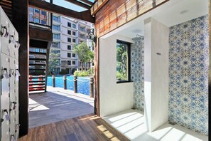 Ein Hotelzimmer mit Blick auf einen Swimmingpool, einer Holzbalkendecke und gemusterten Fliesen.