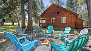 Eine Blockhütte mit Sitzgelegenheiten im Freien und einem Feuerkorb.