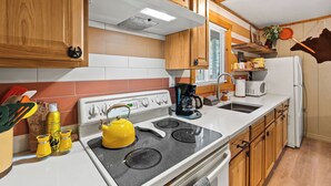 Una cocina con armarios de madera, estufa, fregadero y refrigerador.