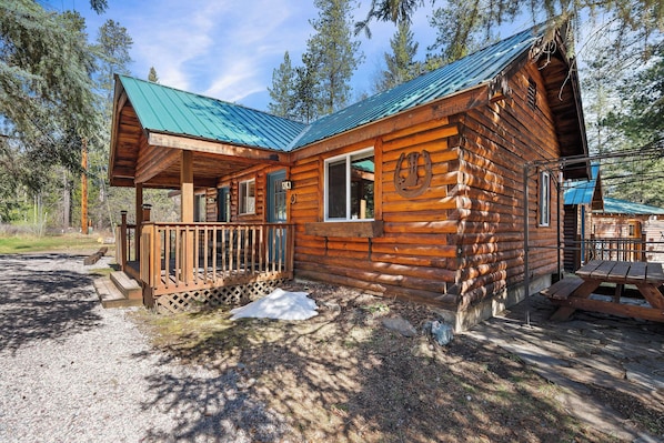 A log cabin with a porch, a covered picnic table, and a horseshoe decoration.