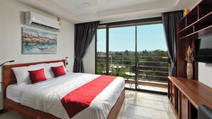 Ein Schlafzimmer mit Bett, Fernseher, Gemälde und einem Balkon mit Tisch und Stühlen.