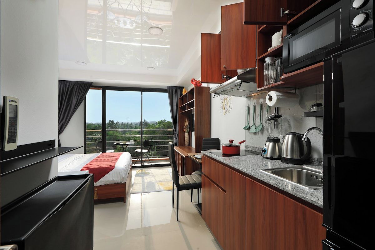 A modern kitchen with a dining area, a bed, and a view of the outdoors.