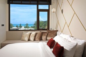 Ein Schlafzimmer mit großem Fenster, einem Bett mit weißen und roten Kissen sowie einem geometrischen Wandmuster.