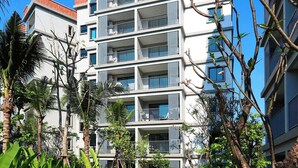 A multi-story hotel with balconies, surrounded by greenery and a paved walkway. - Mountain View Apart Naiyang Beach B704 (Naiyang)