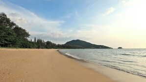 A beach with a sandy shore, a calm sea, and a forested hill in the background. - Mountain View Apart Naiyang Beach B704 (Naiyang)