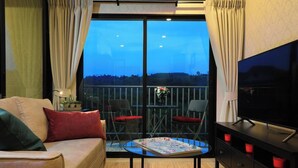A room with a sofa, two chairs, a table with a magazine, a TV, and a balcony with a railing. - Mountain View Apart Naiyang Beach B704 (Naiyang)