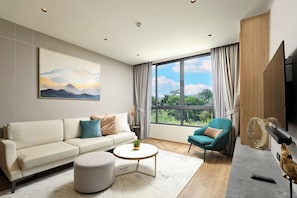 Ein modernes Wohnzimmer mit Sofa, Sessel, rundem Couchtisch und einem Gemälde an der Wand.