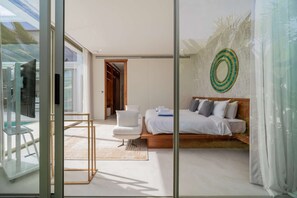 Ein modernes Schlafzimmer mit einem Bett, einem Sessel und einer Glastrennwand.