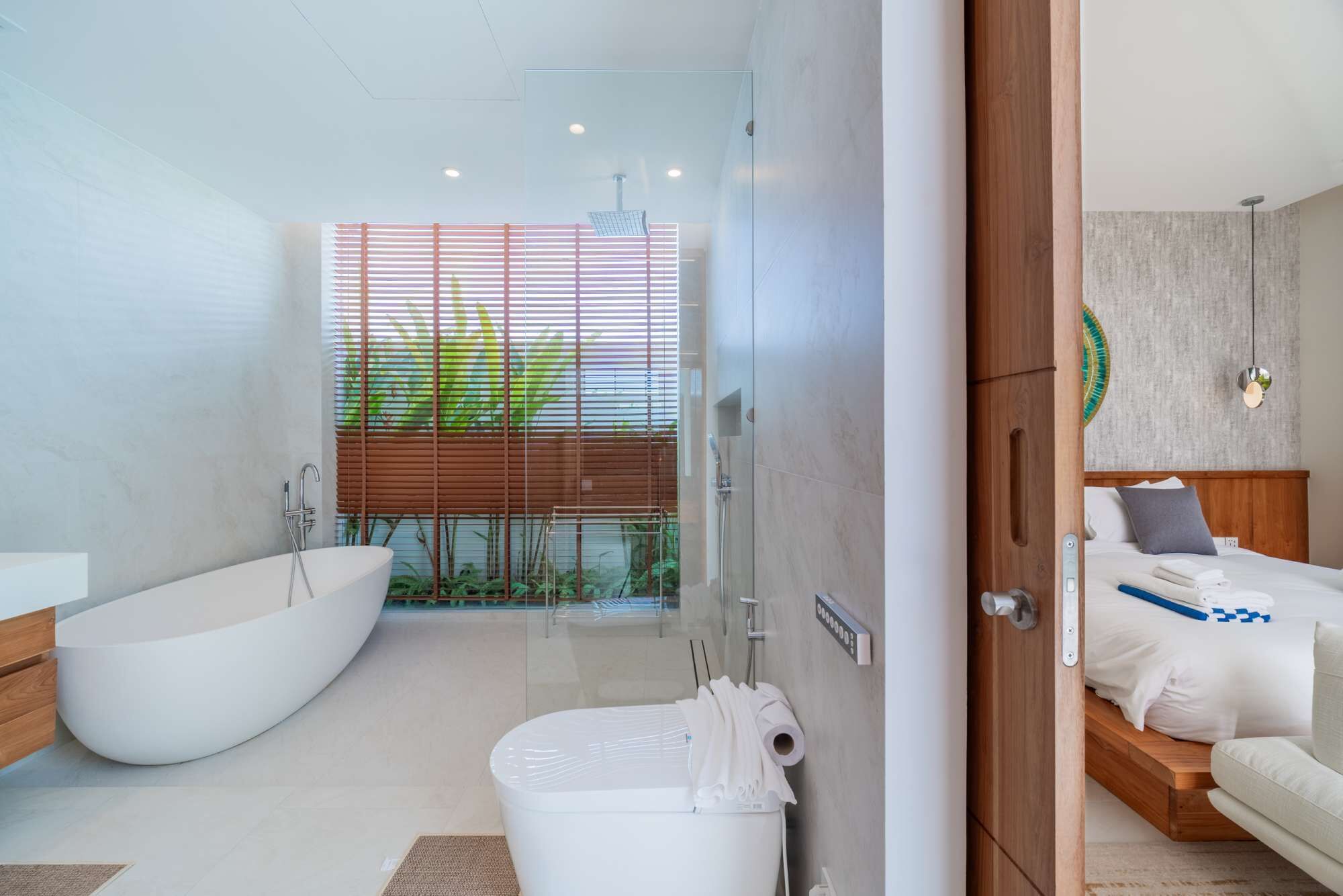 A modern bathroom with a freestanding bathtub, a glass-enclosed shower, and a toilet with a towel rack.