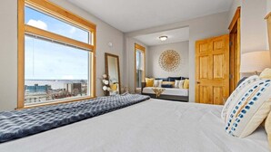 Ein Schlafzimmer mit einem großen Bett, einer Holztür, einem Fenster mit Blick und einem dekorativen Wandbild.
