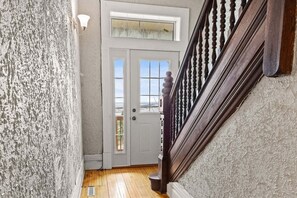 A staircase with a wooden handrail leading to a door with glass panels. - Historic Duluth Home with Lake Views By Heirloom (Duluth)