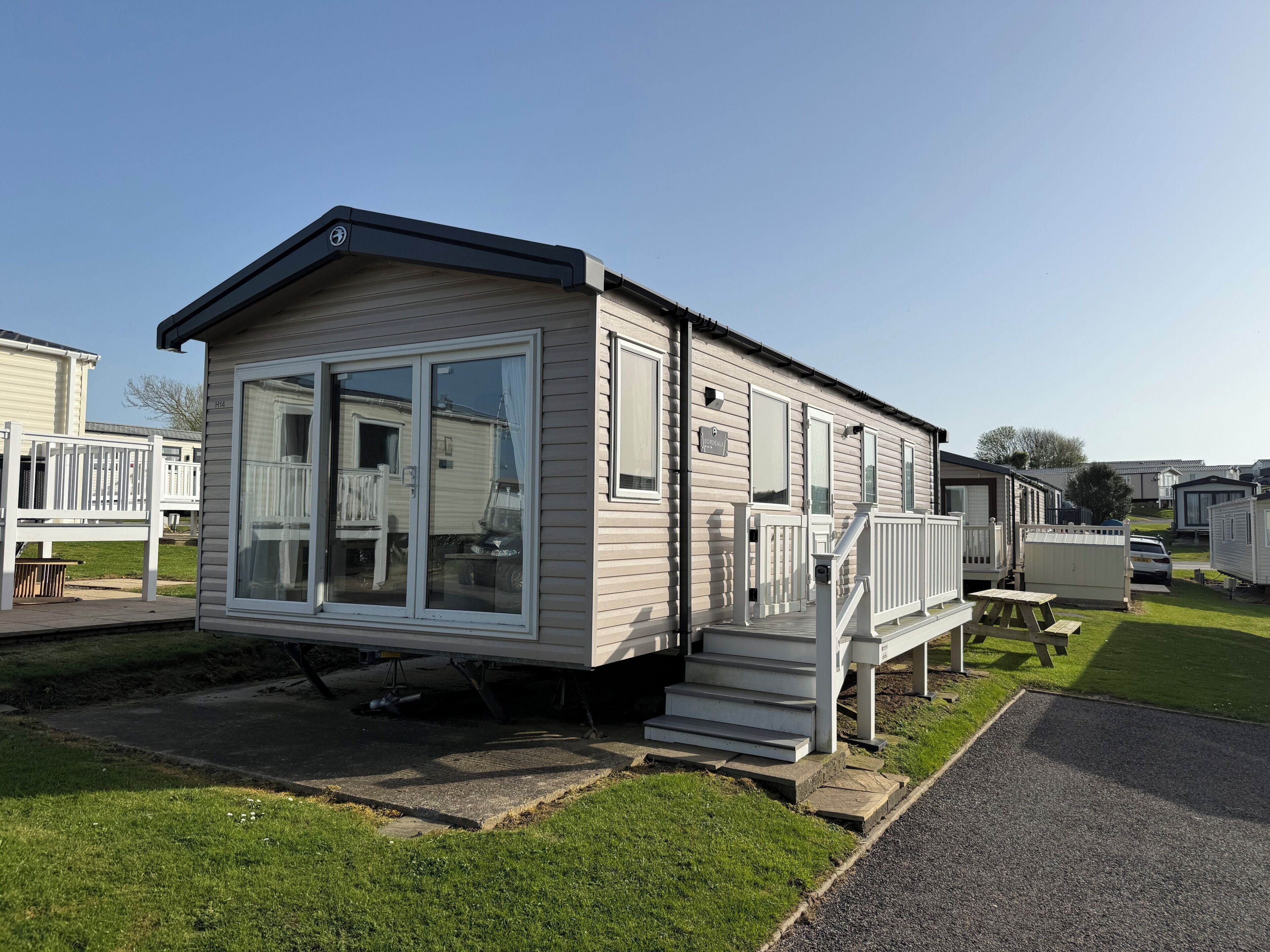 A mobile home with a large sliding glass door, a small porch, and a designated parking area.