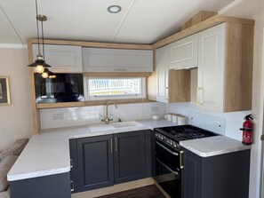 Une cuisine moderne avec un four noir, des plans de travail blancs et des meubles de rangement sombres.