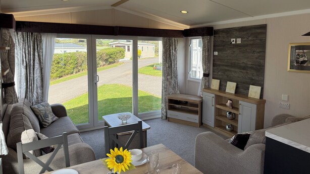 Un interior moderno con zona de comedor, sofá y vistas amplias a través de puertas de cristal.