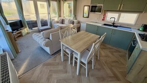 A compact living space with a sofa, dining table, kitchen area, and a television.