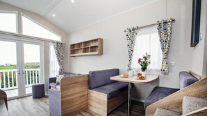 Un interior moderno con una zona de estar, una mesita con un florero y una ventana con cortinas estampadas.