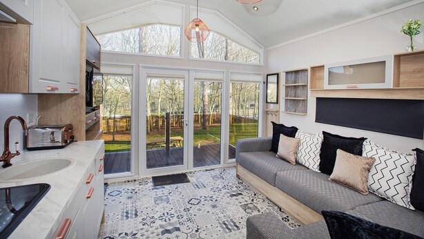 A modern kitchen with a built-in oven, a sink, and a toaster. There is a large window with a view of a backyard.