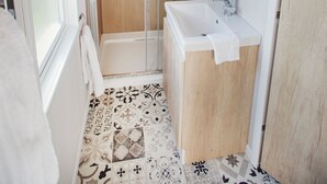 A bathroom with a shower, sink, and a mirror.