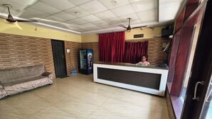 Un área de recepción con mostrador, un sofá, un televisor y un ventilador de techo.