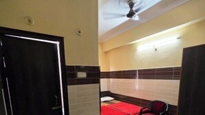 Habitación de hotel con cama, una silla, armario, ventilador de techo y suelo de baldosas.