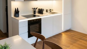 Una cocina moderna con armarios blancos, una encimera negra y un horno empotrado.