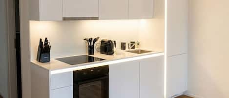 Una cocina moderna con armarios blancos, una encimera negra y un horno empotrado.